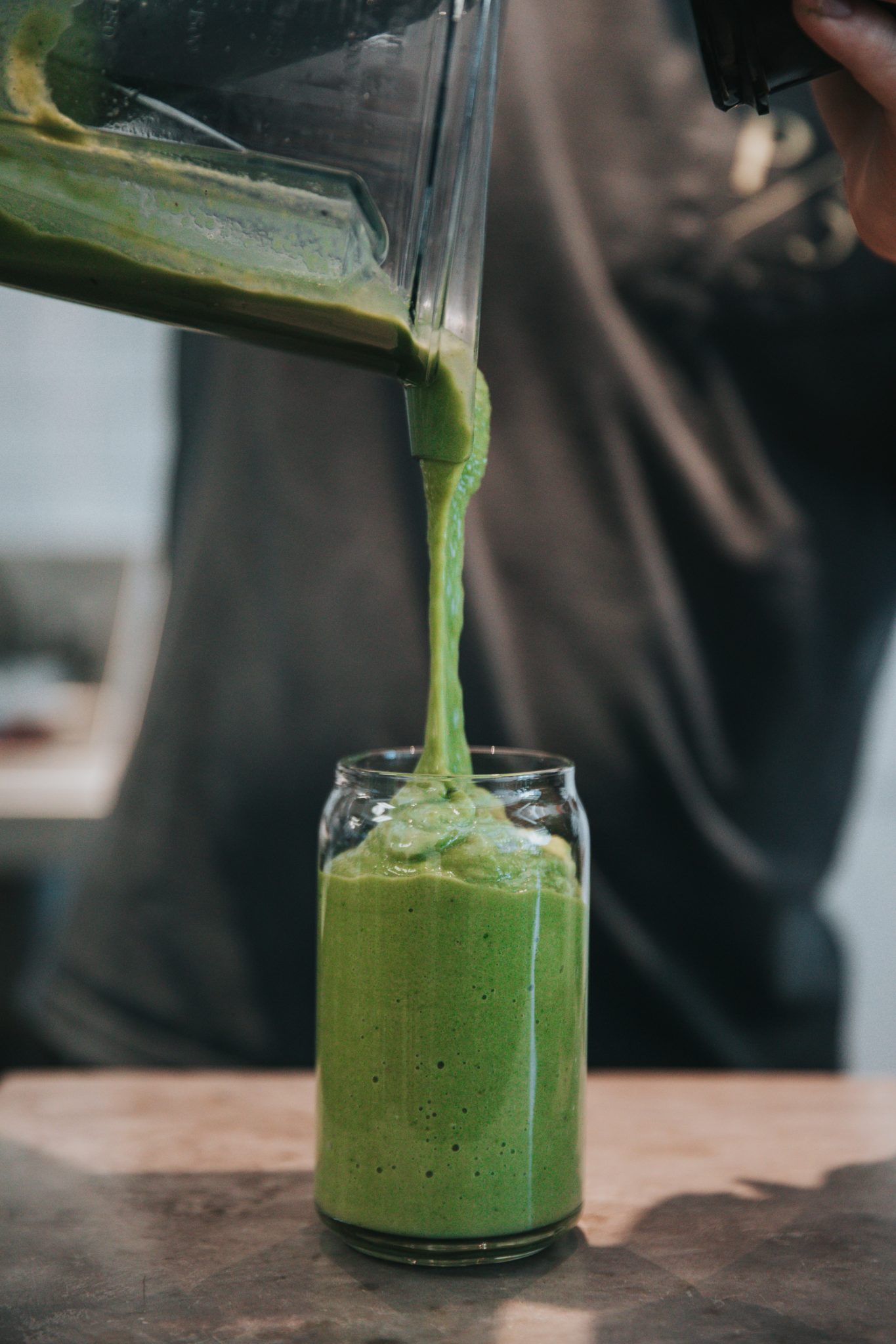 close up of a green smoothie being poured into a tall clear glass from a blender for bariatric surgery diet