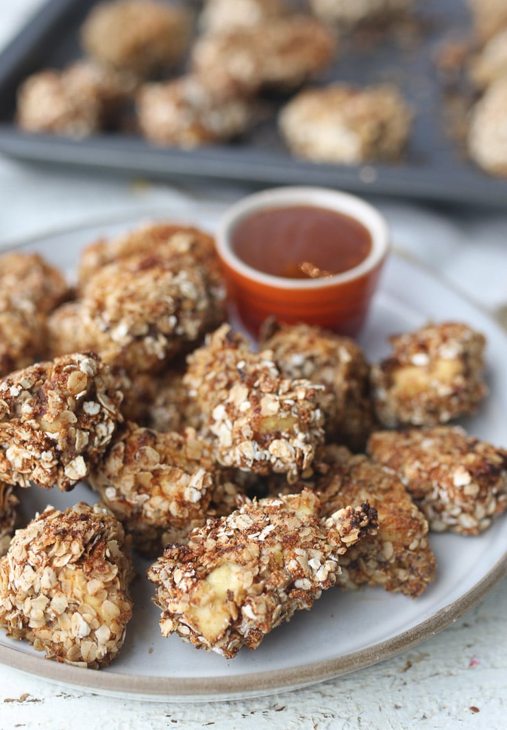 Plate of tofu nuggets made with oatmeal with a sweet and sour sauce in a red ramekin.