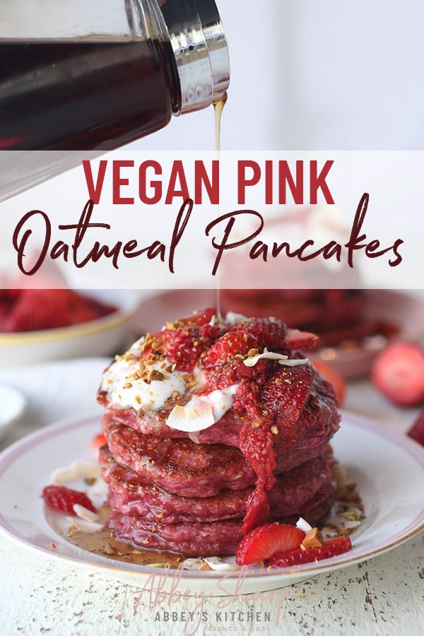 pinterest image of a stack of no sugar added pink oatmeal pancakes garnished with fresh fruit, and nuts on a white plate with maple syrup being poured on top