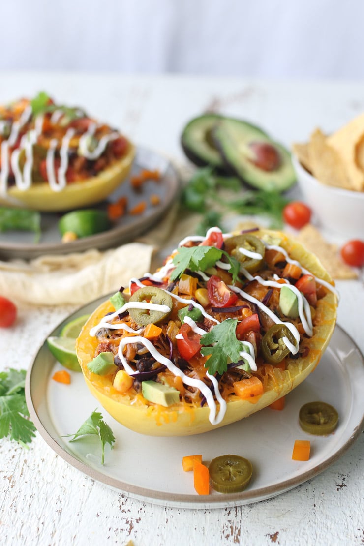 spaghetti squash burrito bowl on a white plate topped with cilantro and sour cream