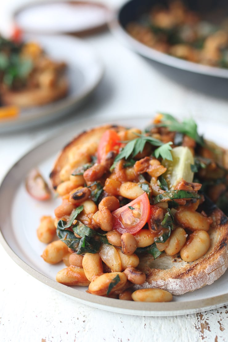 Close up of toast with navy beans and garnished with tomato and parsley.