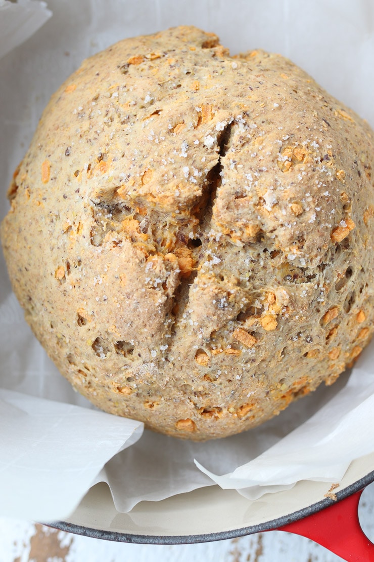 close up of soda bread loaf in a red pan with parchment paper underneath