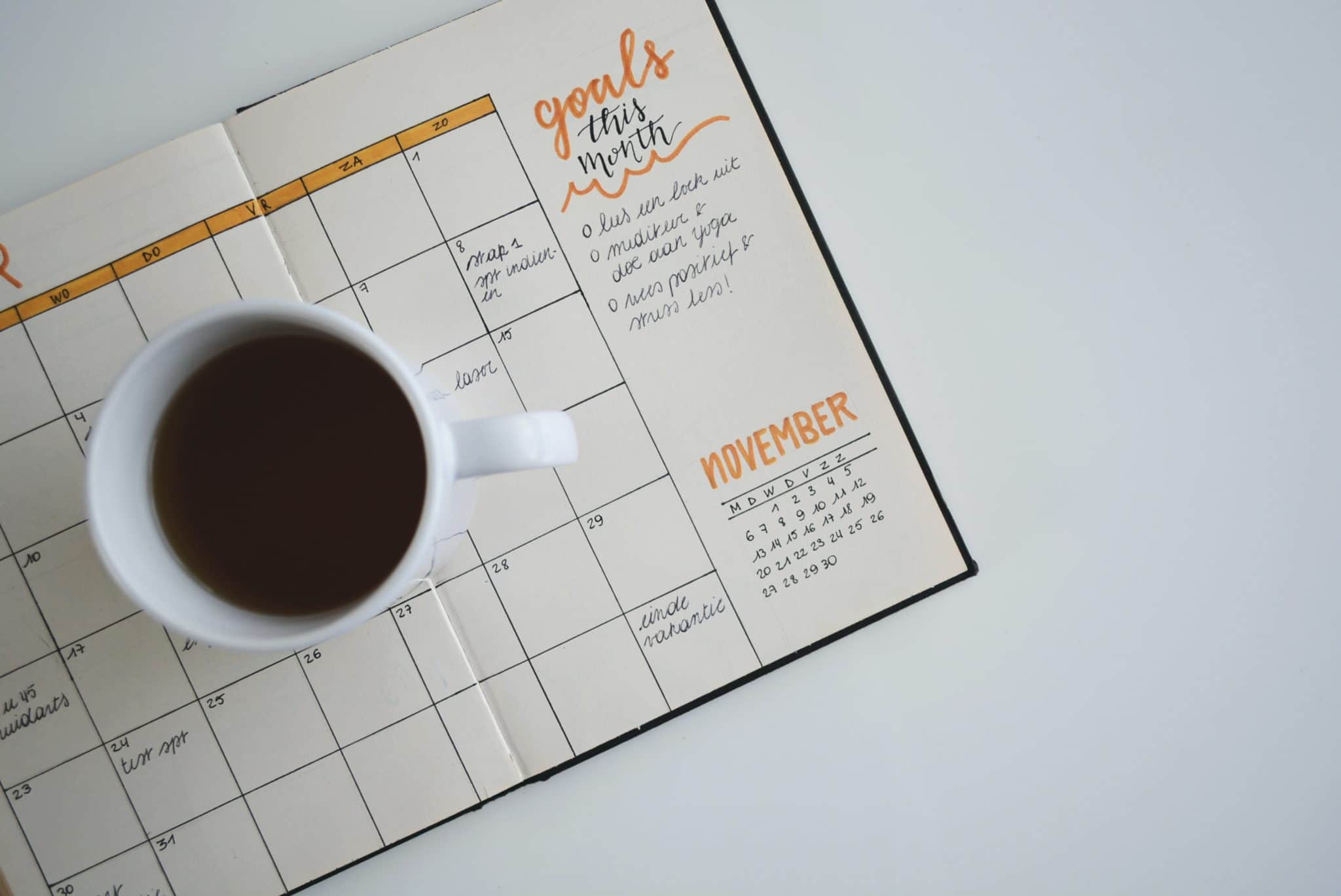 A day planner with a list of goals and a cup of coffee sitting on top.