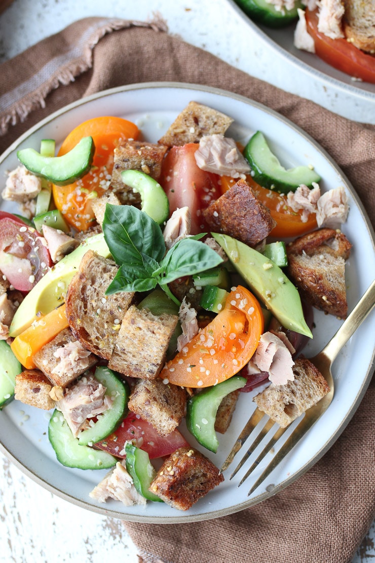 close up of italian tuna avocado salad garnished with basil 