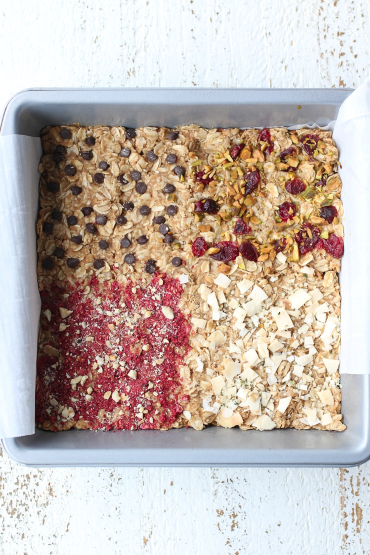 Birds eye view of oatmeal bars in a pan with different toppings like chocolate chips, dried fruit, and coconut.