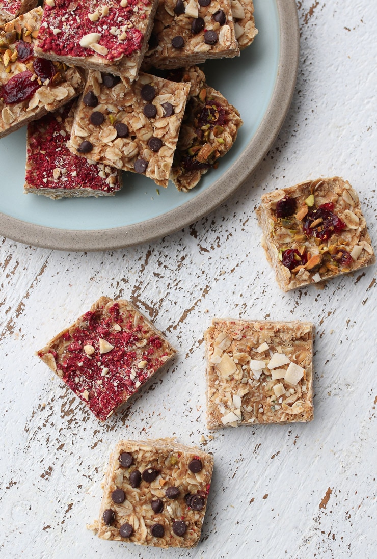 Birds eye view of oatmeal bars with a variety of different topping like chocolate chips, coconut flakes, and freeze dried fruit.