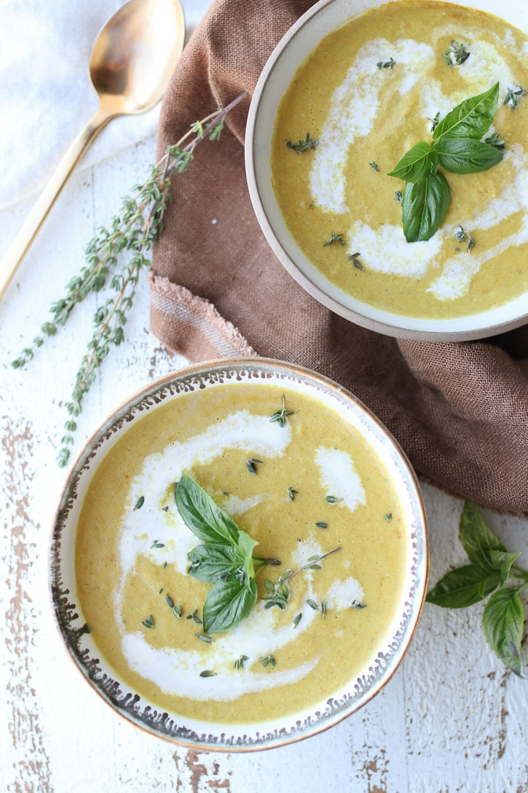 birds eye view of two bowls of vegan corn soup garnished with fresh basil and thyme 