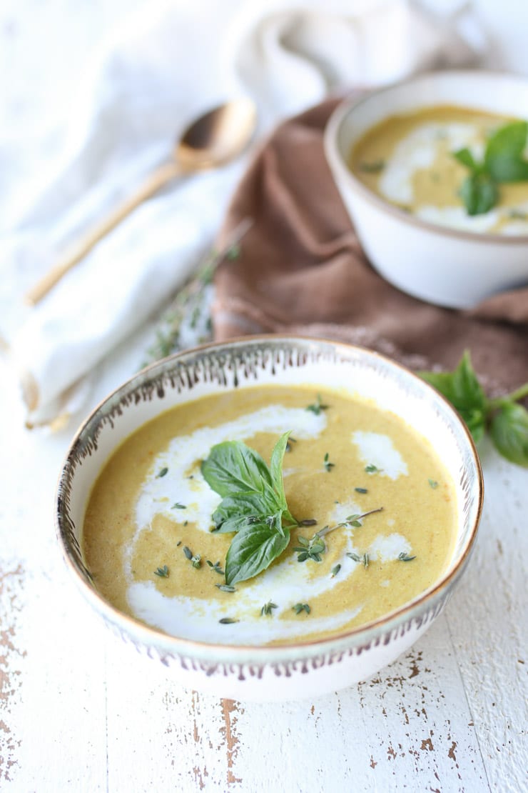 vegan corn soup in a white bowl topped with basil 