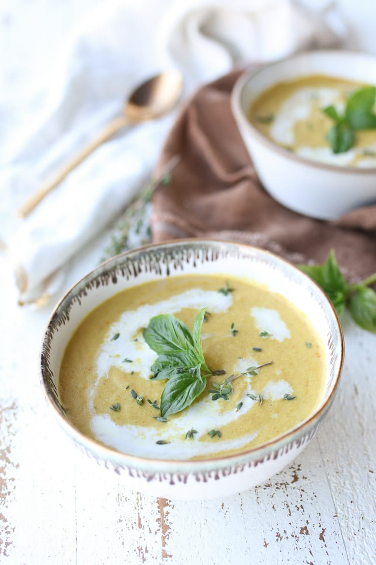 Vegan corn soup in a white bowl topped with basil.