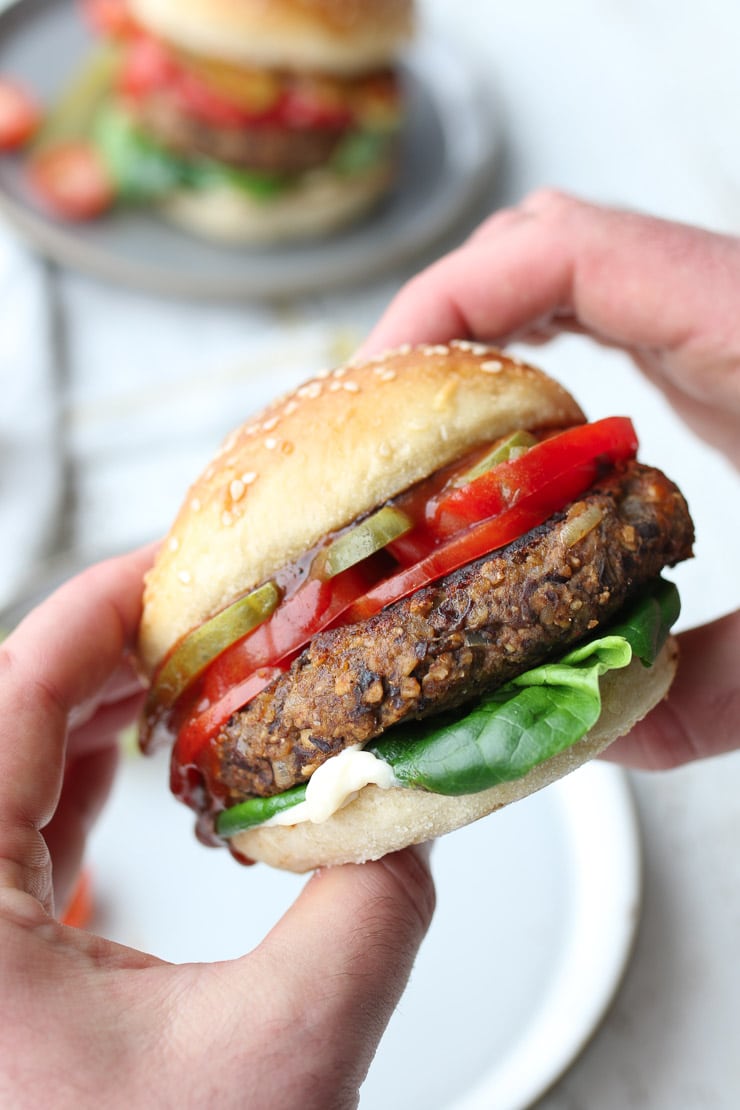 Close up of two hands holding up spicy black bean burger. 