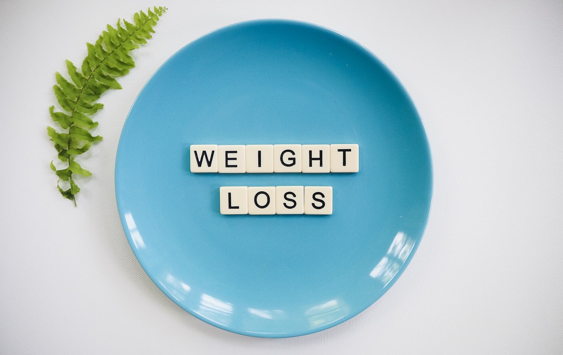 A blue plate with the words "weight loss" spelled out in white tiles.