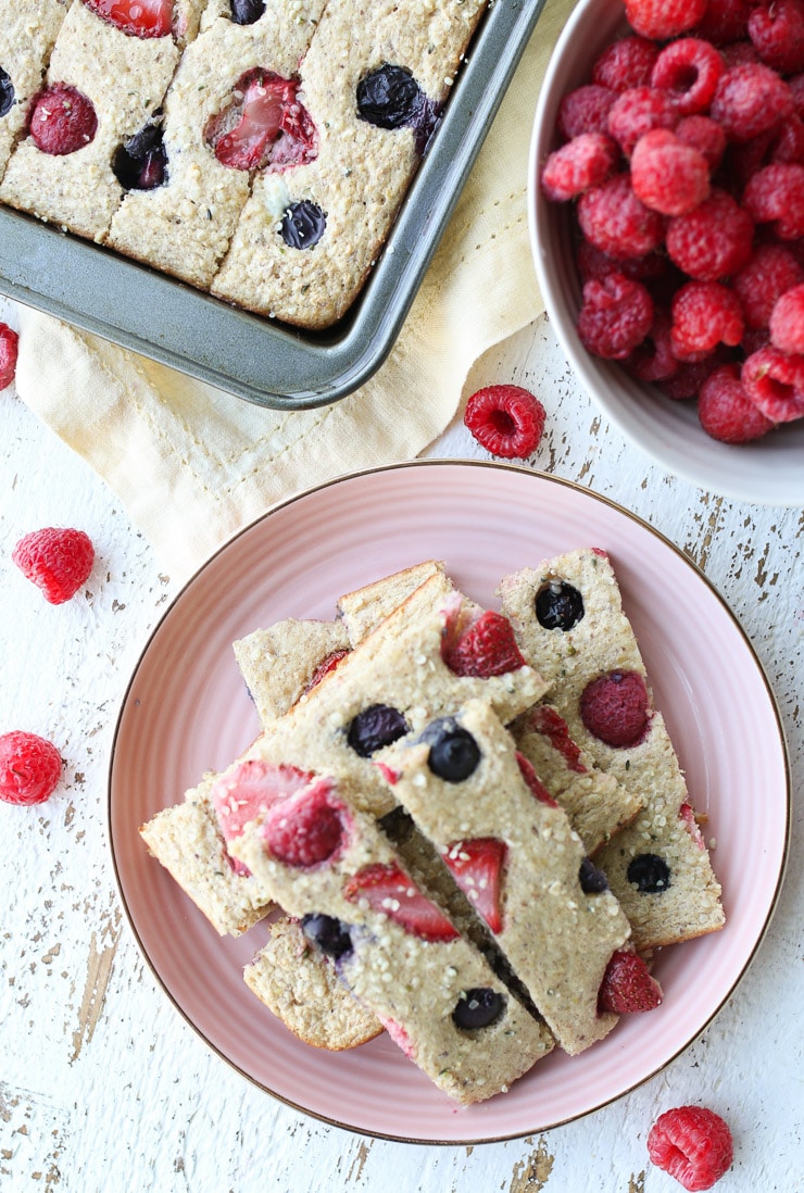 birds eye view of berry pancake fingers on a pink plate with sheet pan and raspberries in the background