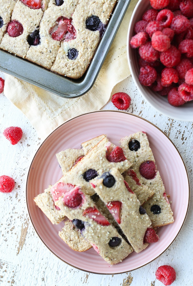 birds eye view of berry pancake fingers on a pink plate with sheet pan and raspberries in the background 