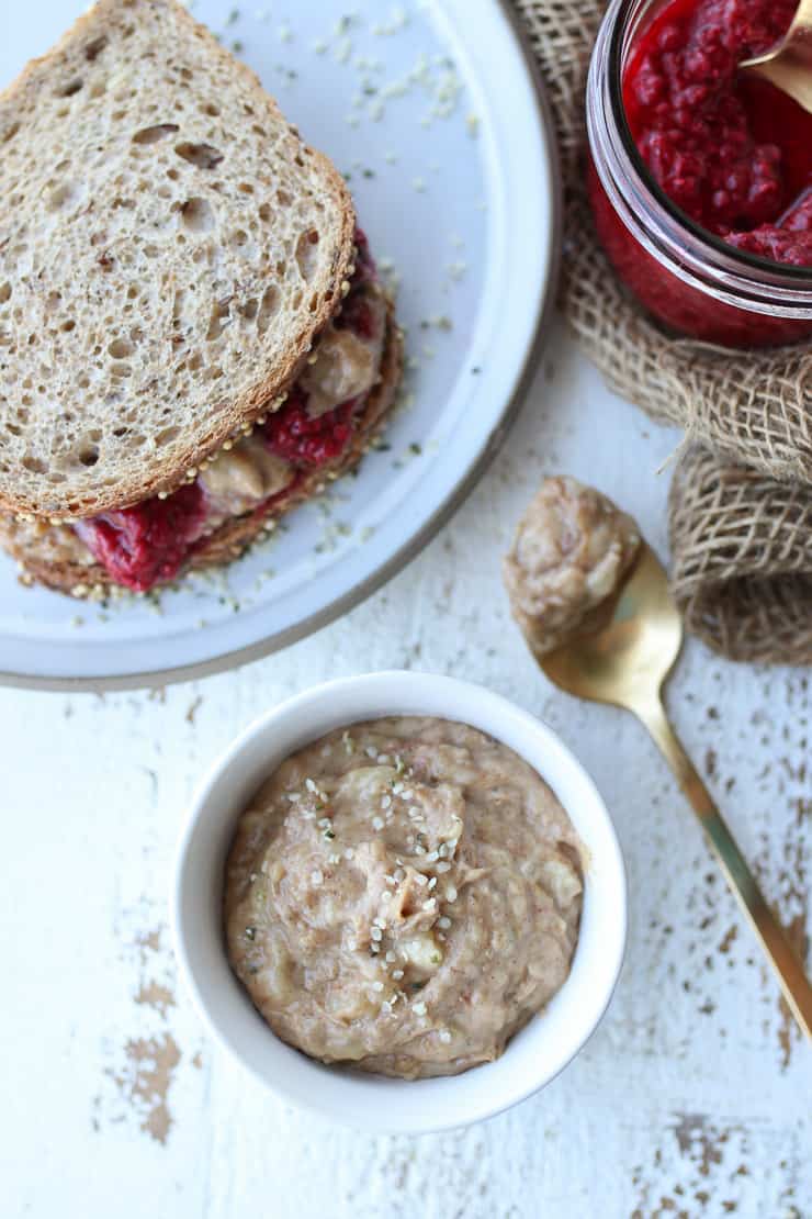 birds eye view of peanut butter in a white bowl with a sandwich on the side .