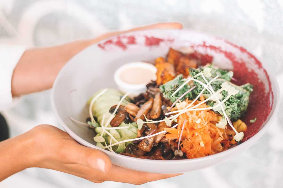 Person holding bowl of food for how to fix a slow metabolism.