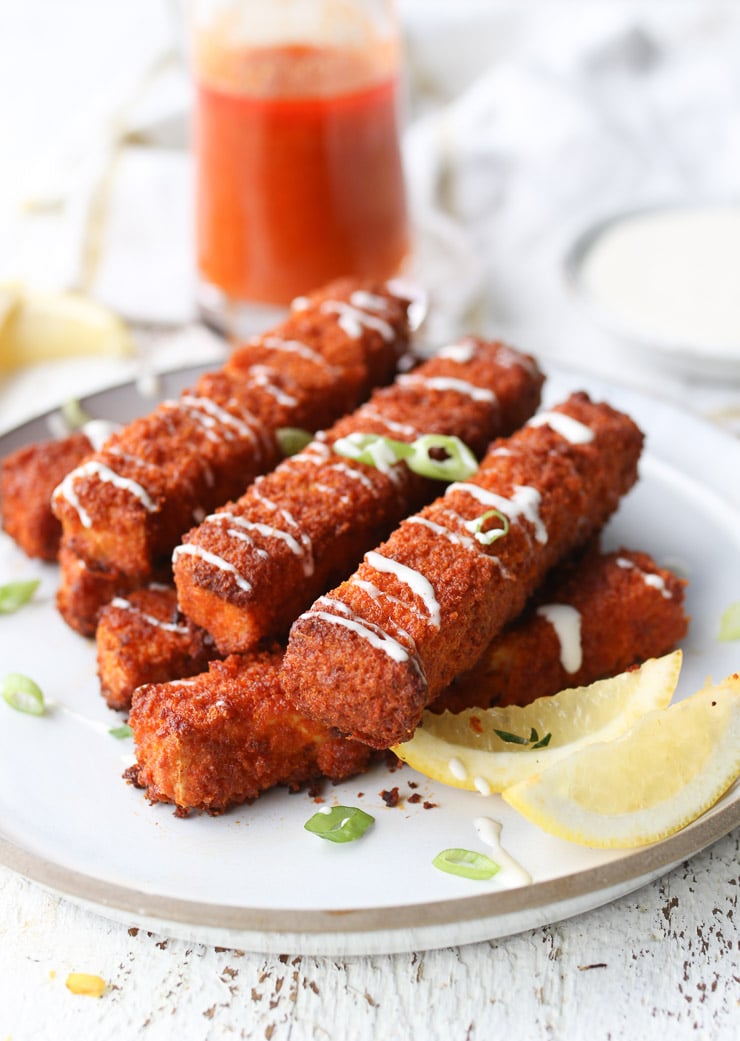 several vegan buffalo sticks on a plate drizzled with sauce 