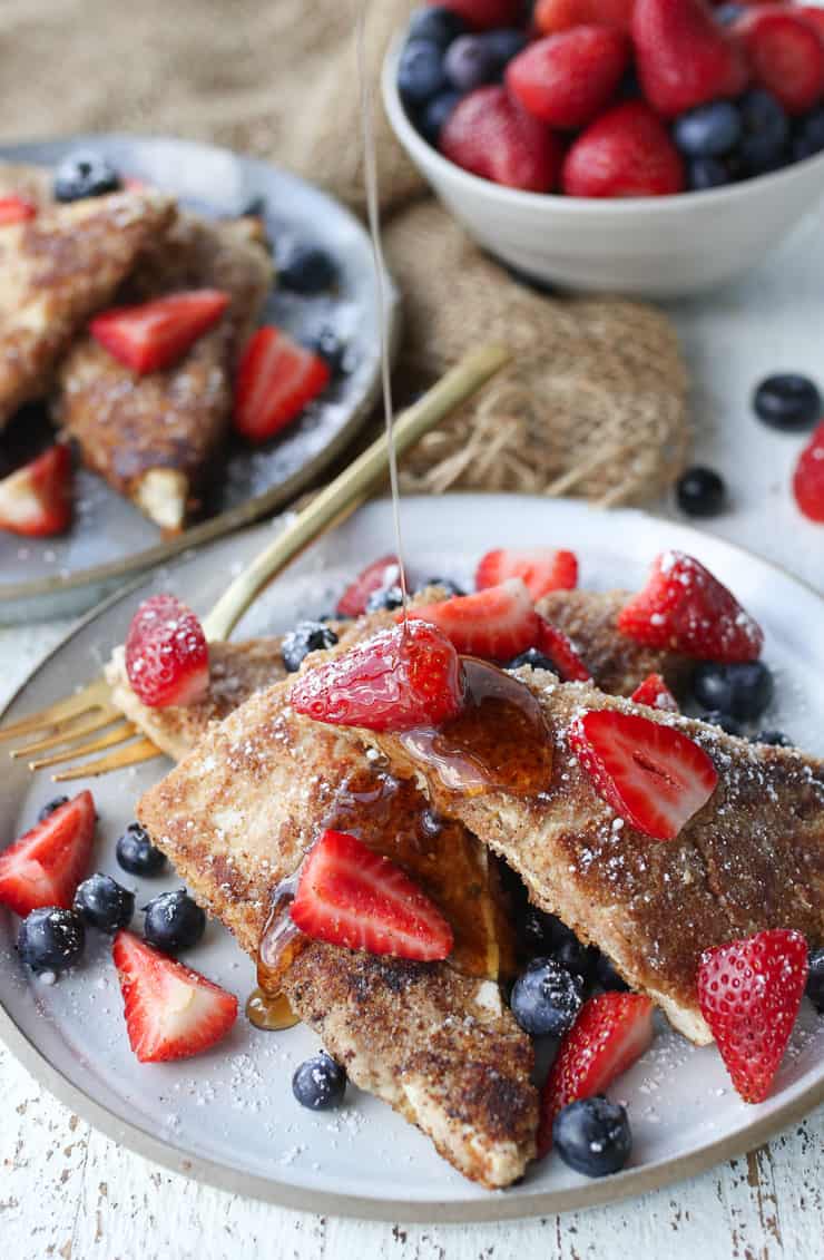 close up of french toast made from tofu on a white plate topped with berries
