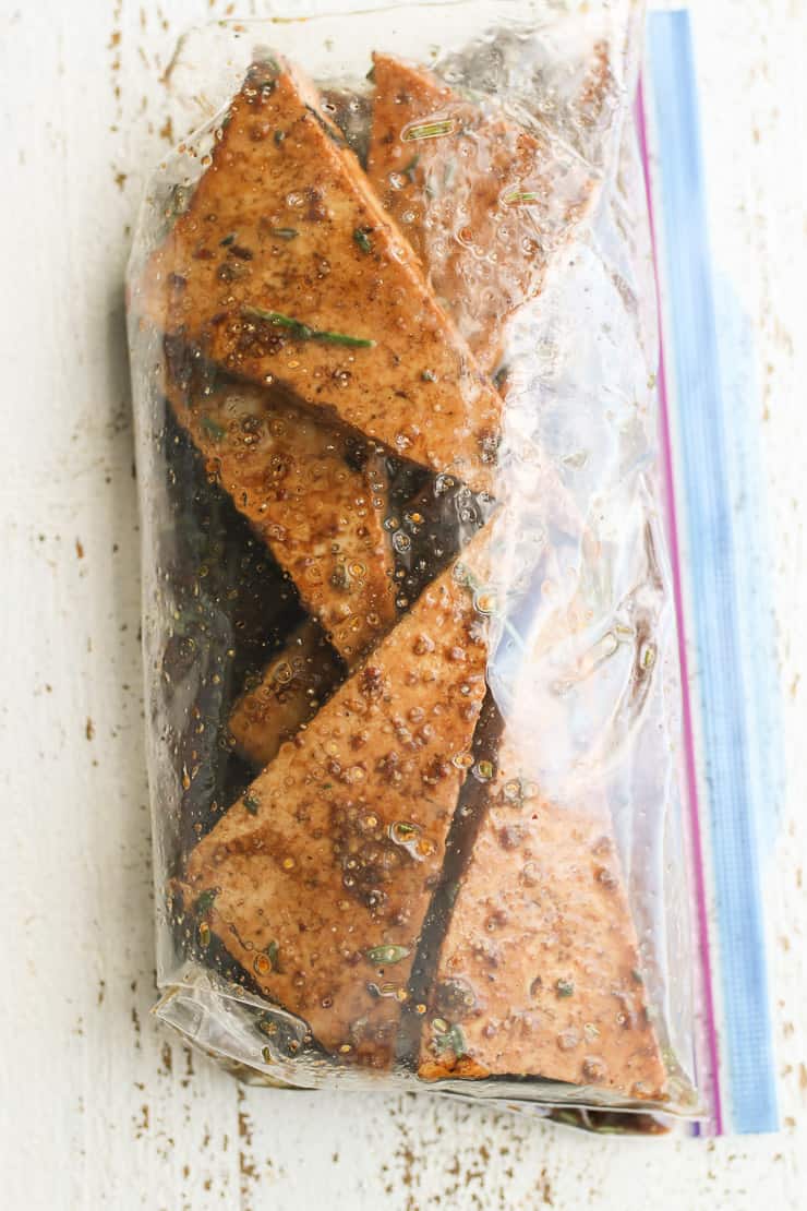 several pieces of tofu in a bag being marinaded in a variety of herbs and spices 