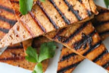 several pieces of grilled tofu on a white plate garnished with cilantro