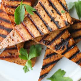 several pieces of grilled tofu on a white plate garnished with cilantro