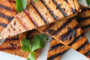 several pieces of grilled tofu on a white plate garnished with cilantro