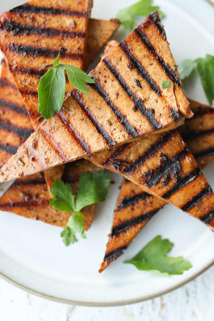 several pieces of grilled tofu on a white plate garnished with cilantro 