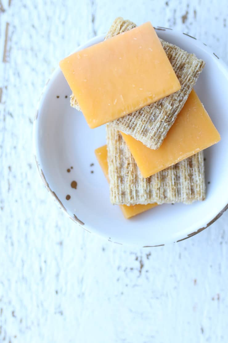 whole grain crackers and cheese on a white plate 