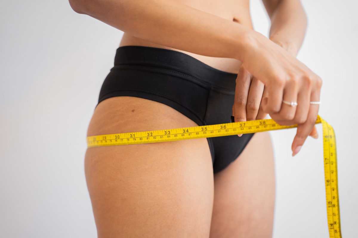 Woman measuring her hips to determine weight set point.