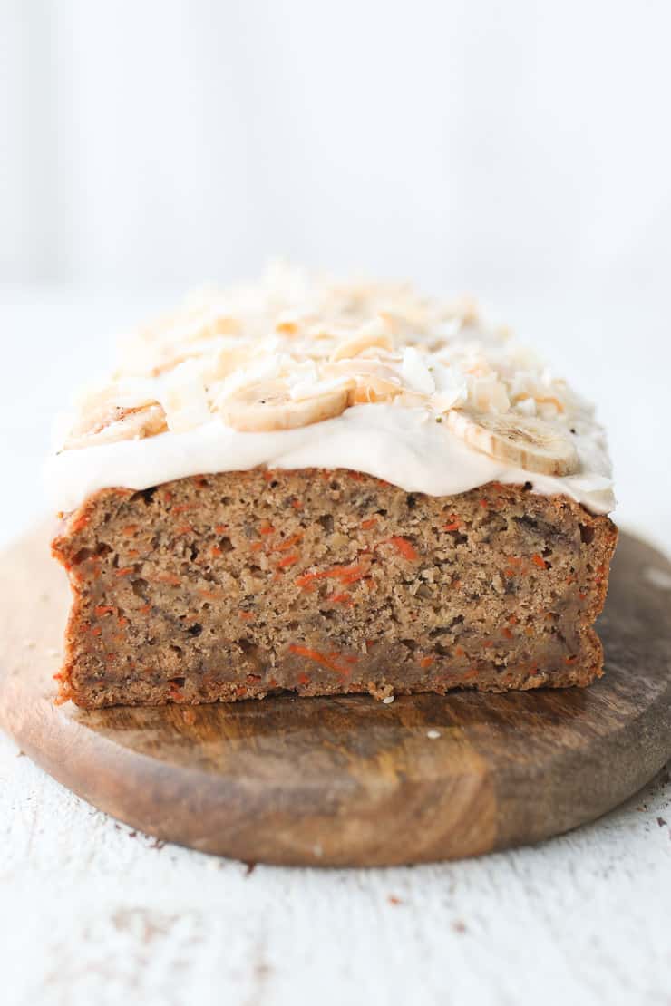 Banana Carrot Cake cut in half topped with cream cheese.