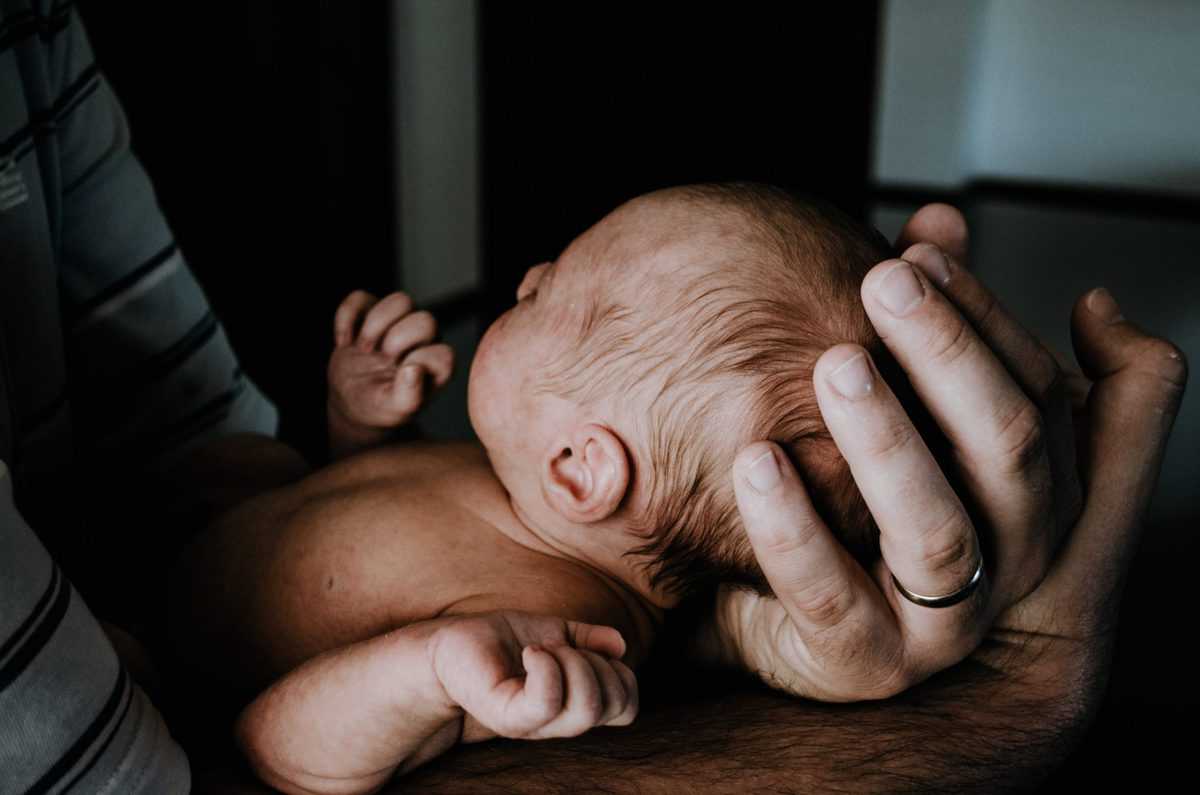 A newborn baby being held in someones hands.