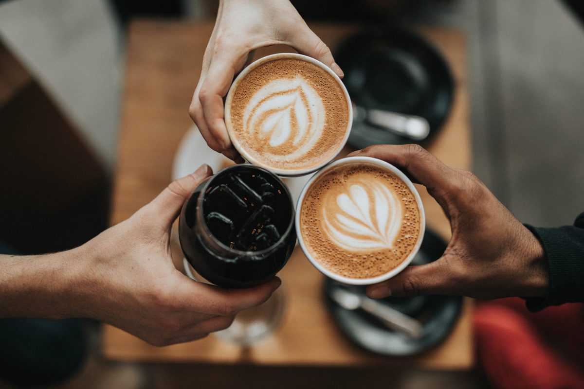 Three people cheersing with caffeinated beverages.