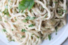 birds eye view of fettuccini alredo pasta on a white plate garnished with parsley