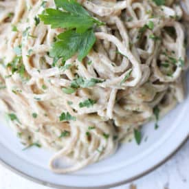 birds eye view of fettuccini alredo pasta on a white plate garnished with parsley