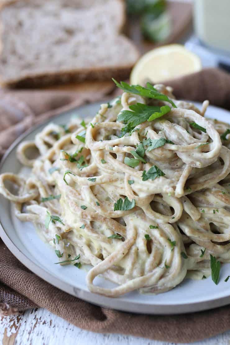 close up of vegan fettuccini alfredo on a white plate.