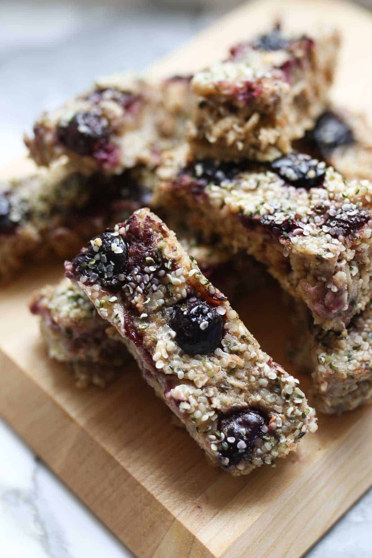 Several banana baked oatmeal fingers stacked on a wooden board.