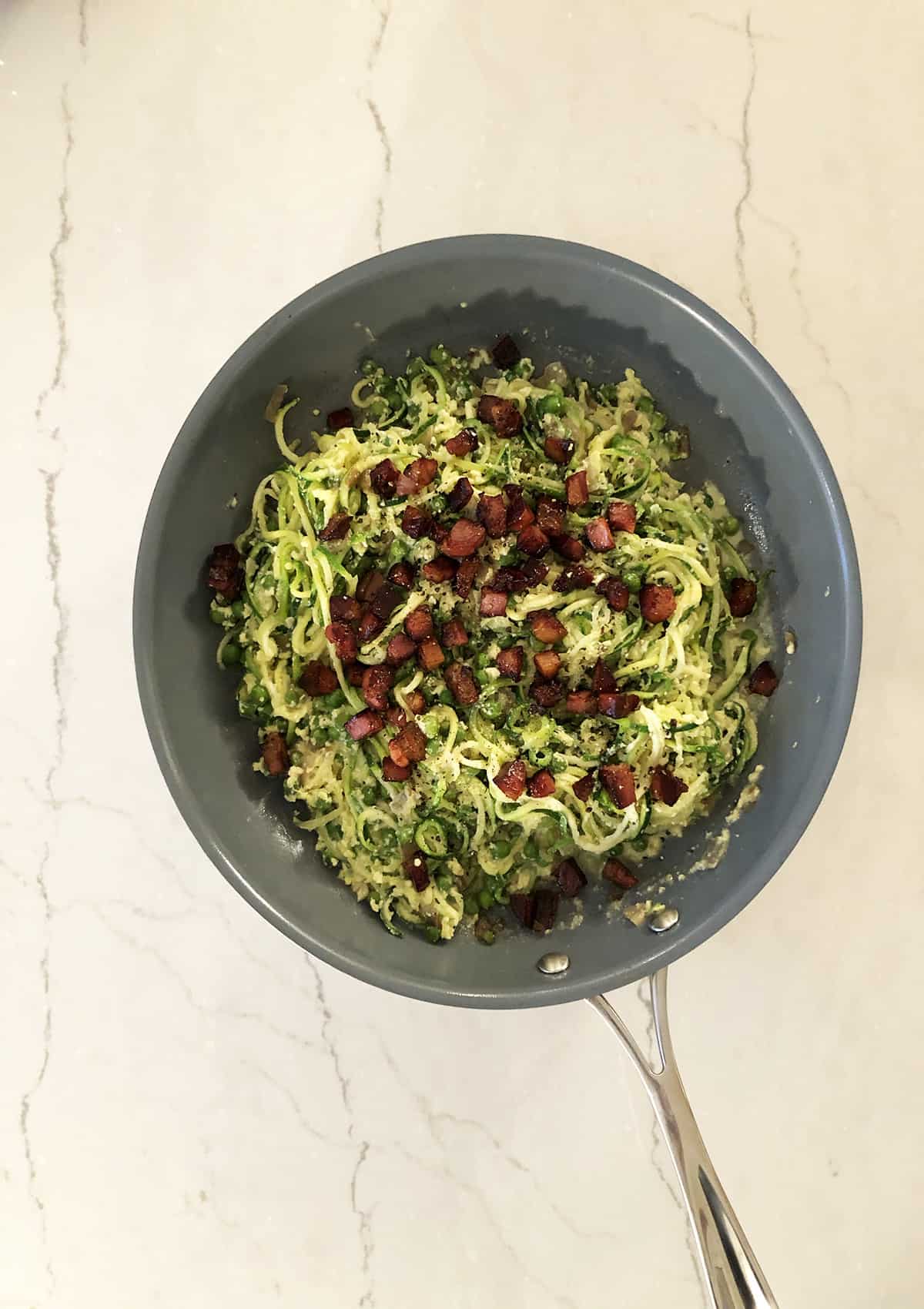 Zucchini zoodles carbonara with pancetta in frying pan. 