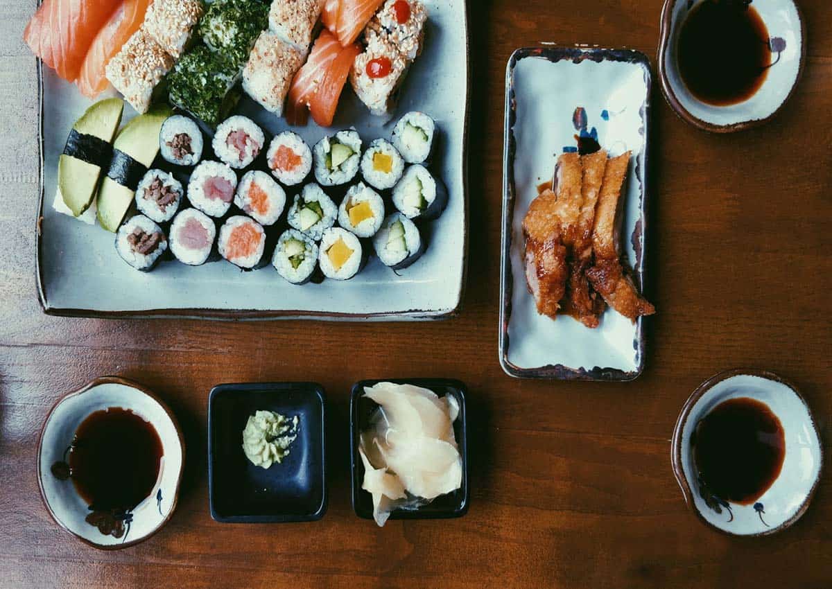 Birds eye view of a sushi platter with dishes filled with soy sauce. 