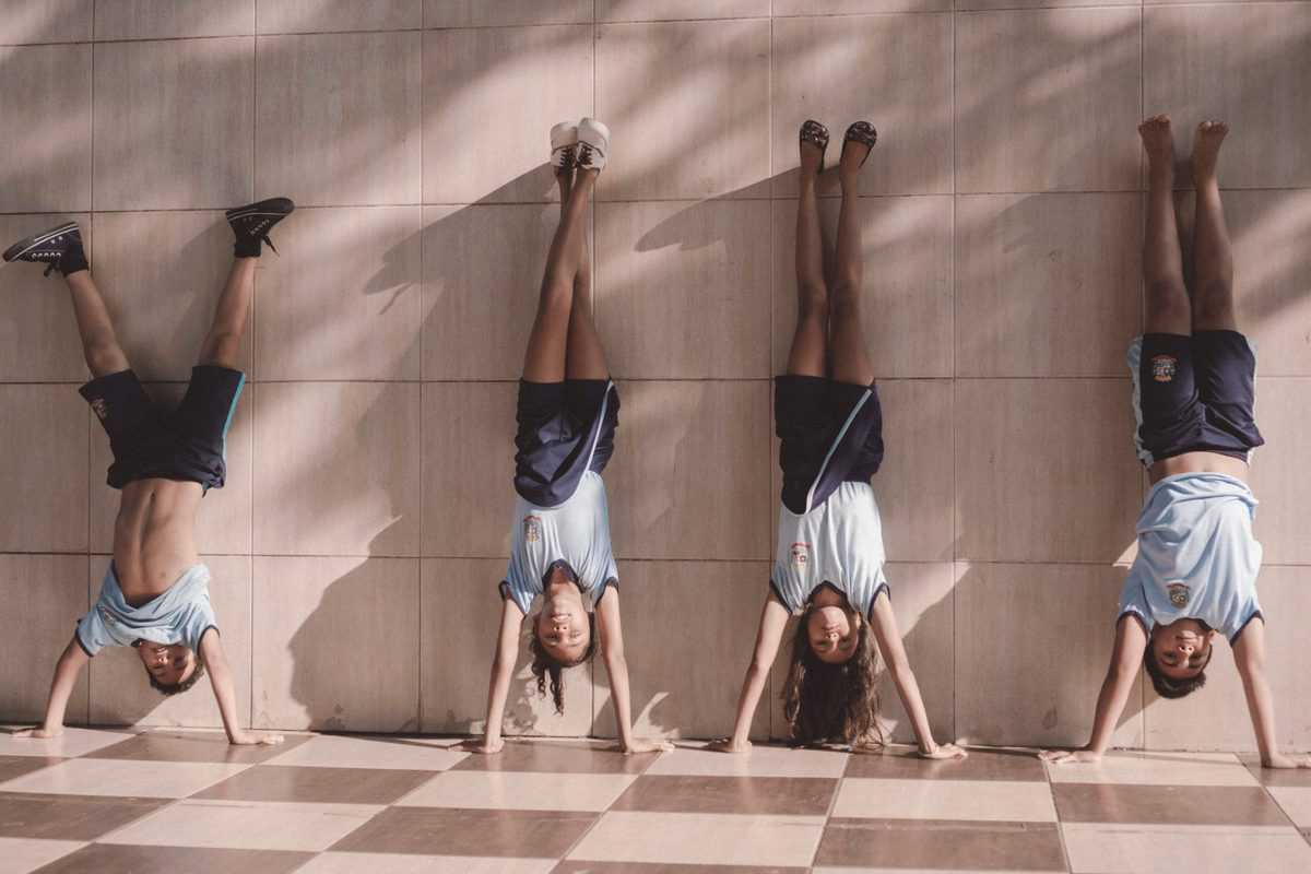 Four girls doing handstands against a wall.