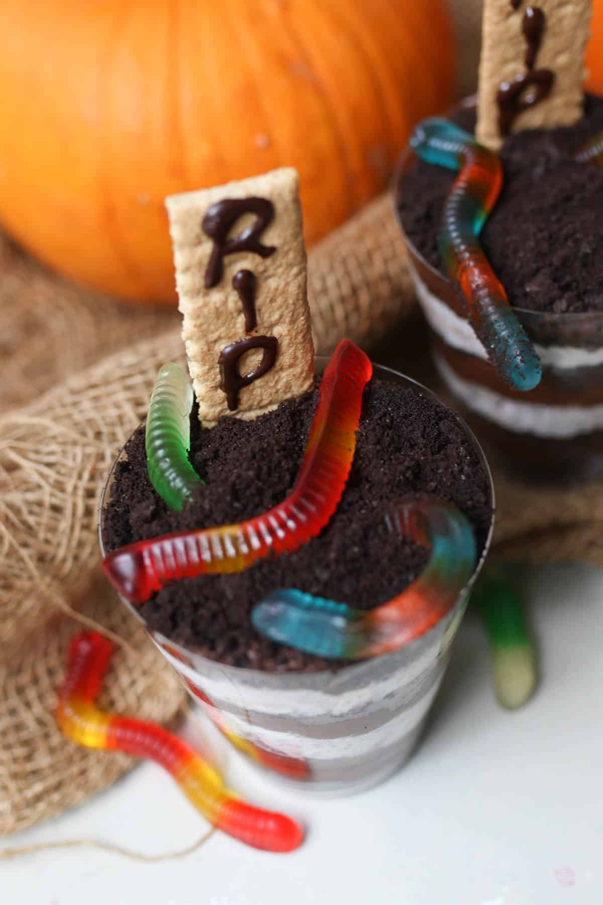 Birds eye view of halloween cups with colourful gummy worms on top. 