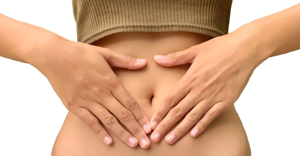 Woman in a brown shirt touching her stomach with both hands.  