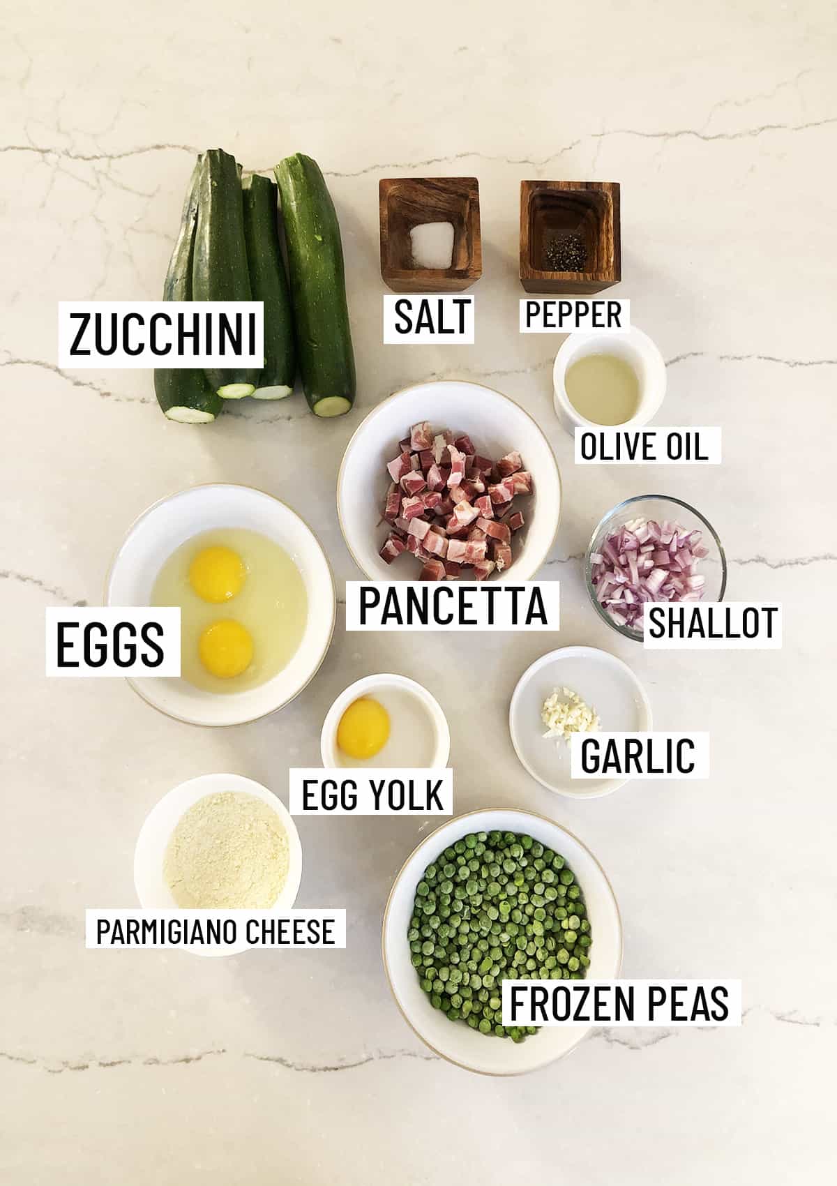 Birds eye view of ingredients for zoodles carbonara portioned out in to individual bowls.