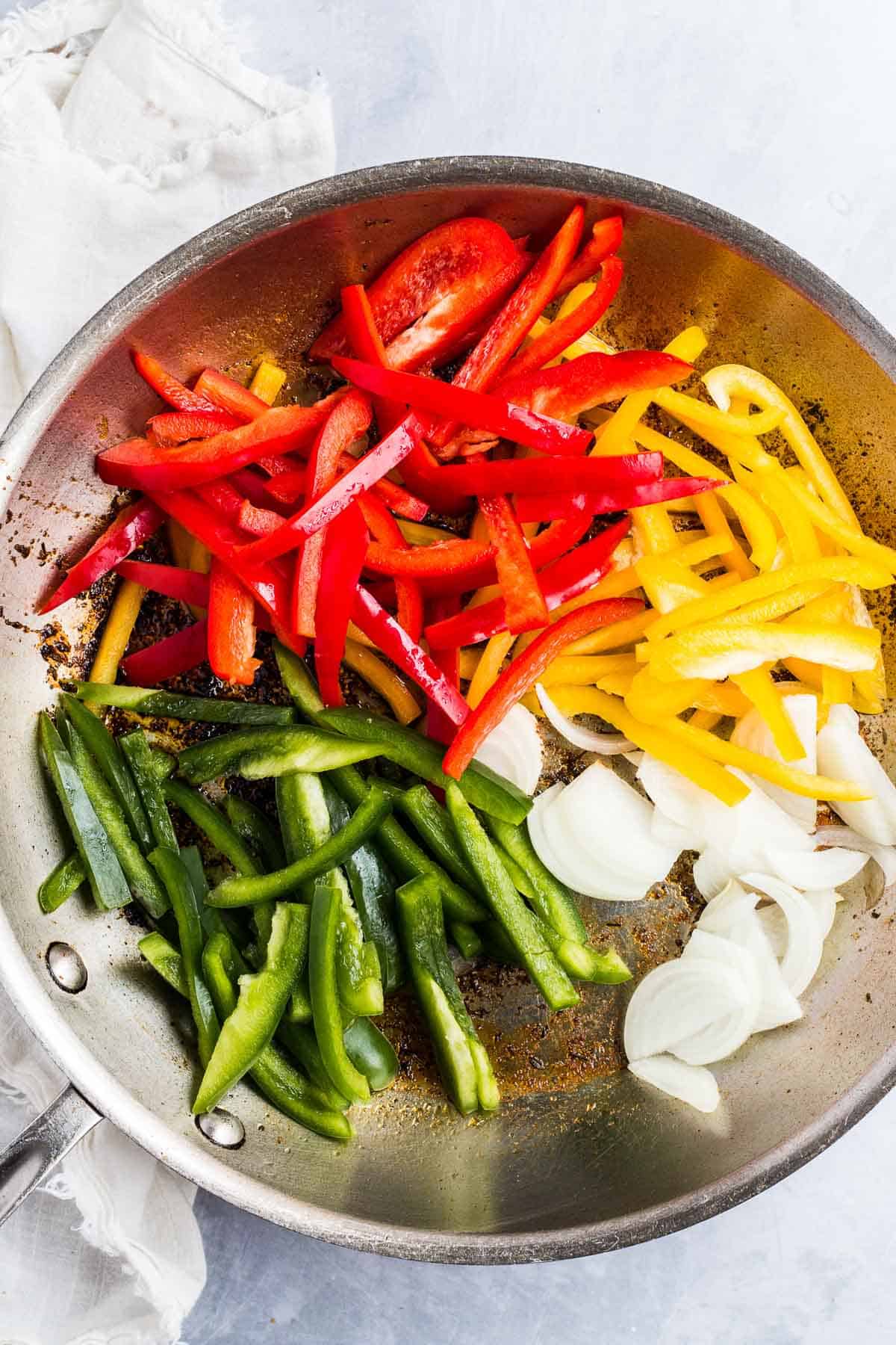 Bell peppers and onions in a frying pan.