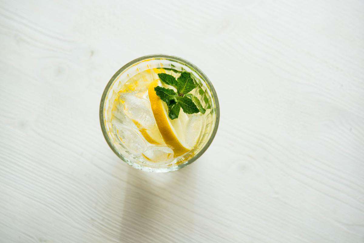 Birds eye view of a glass of lemon water with a mint sprig. 