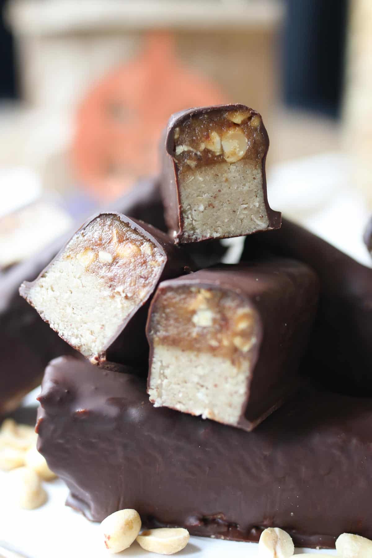 Several healthy homemade vegan Snickers bars stacked on top of one another. 