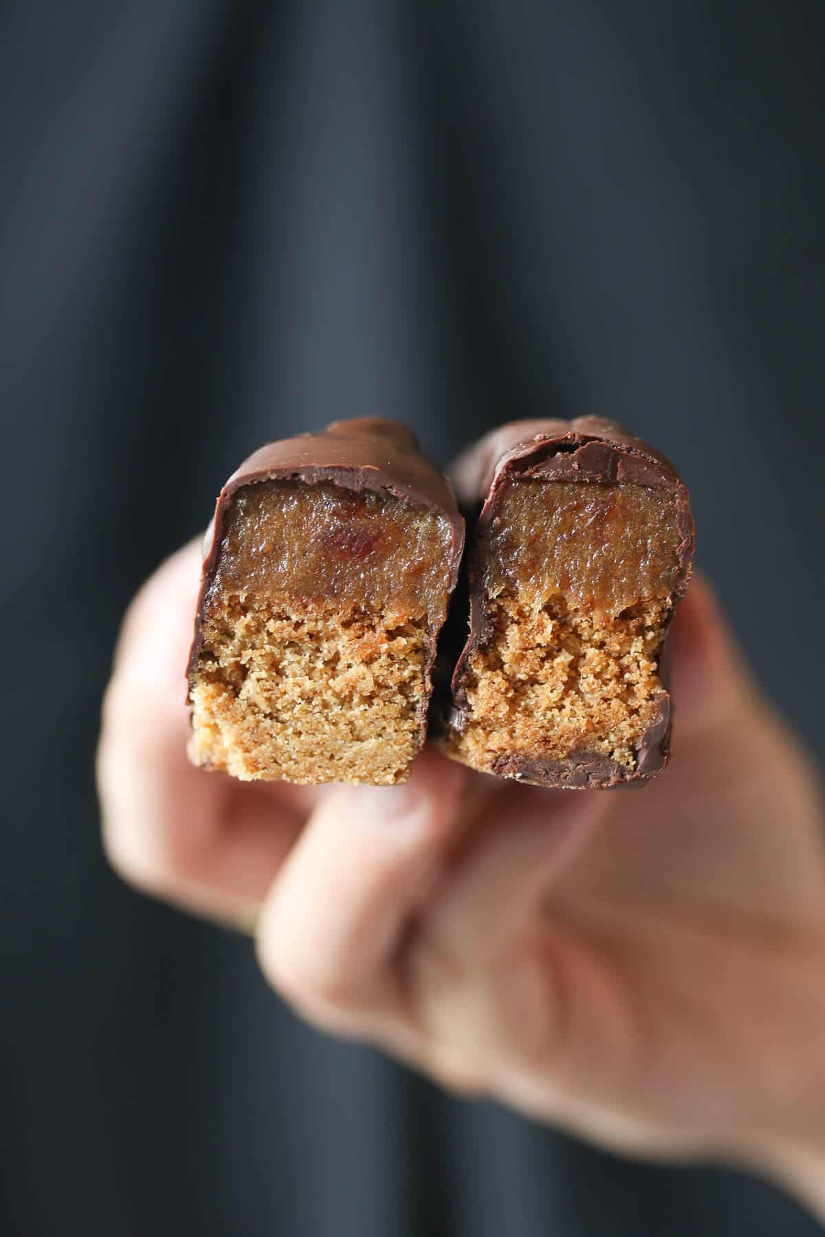 A hand holding up two pieces of a homemade Twix bars. 