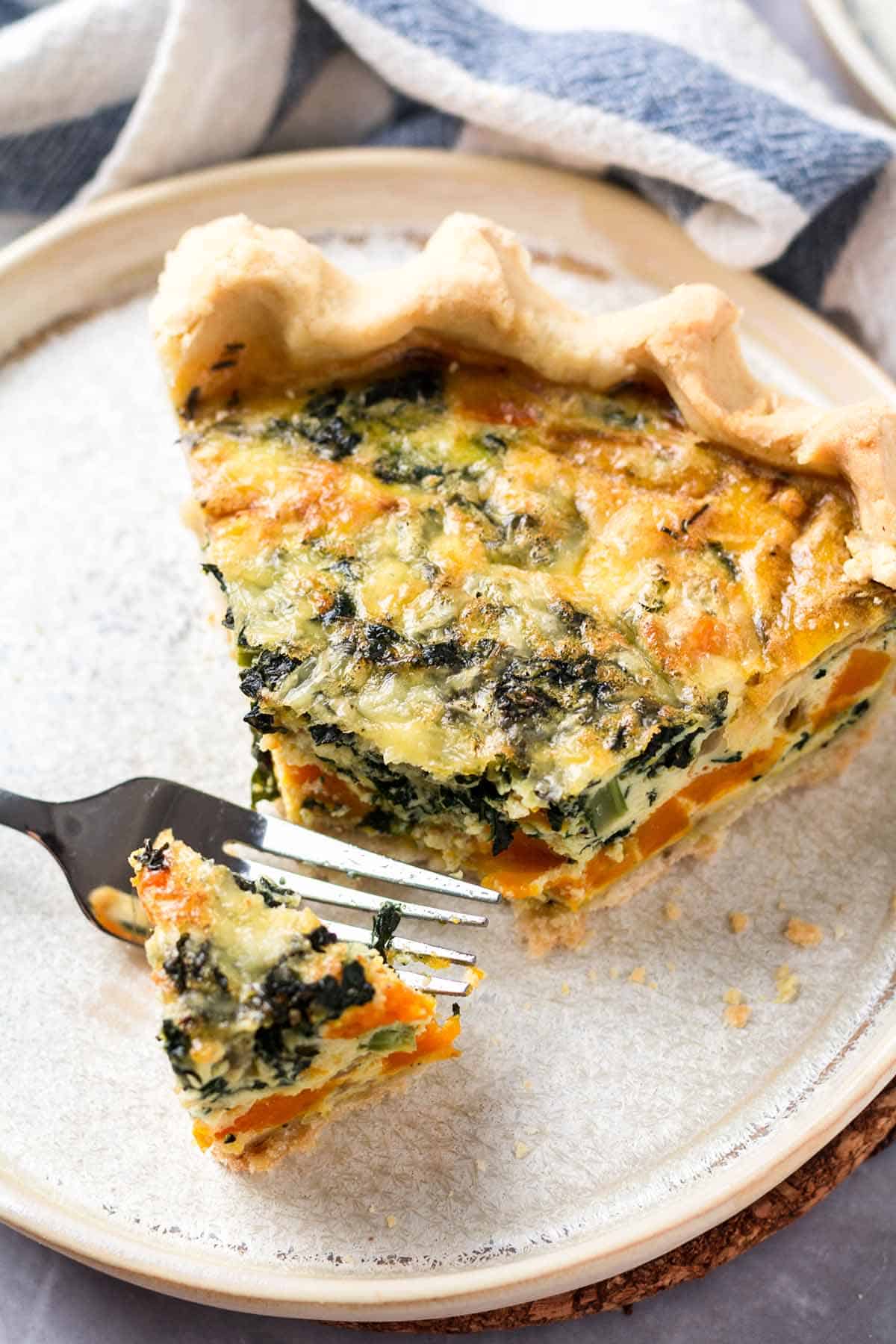 A slice of gluten free quiche on a plate.  