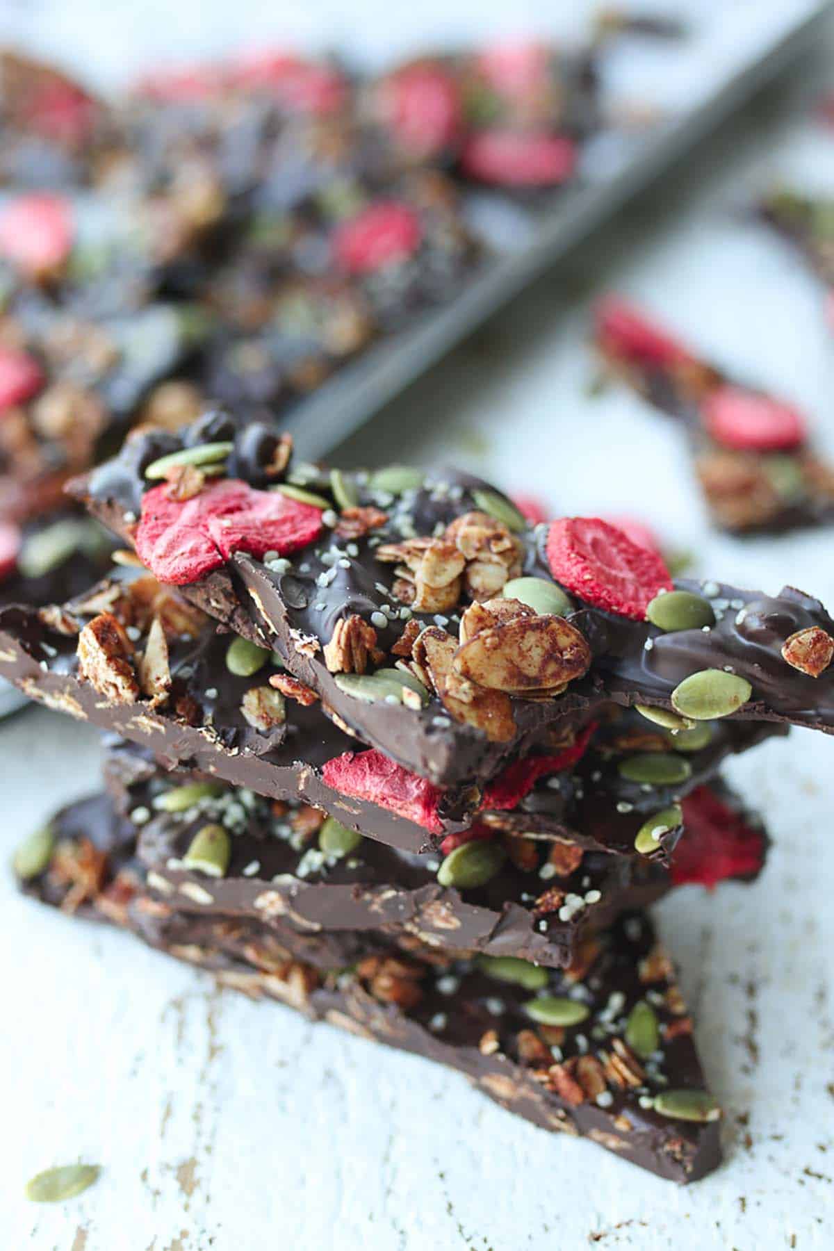 Several pieces of dark almond chocolate bark stacked on top of one another.