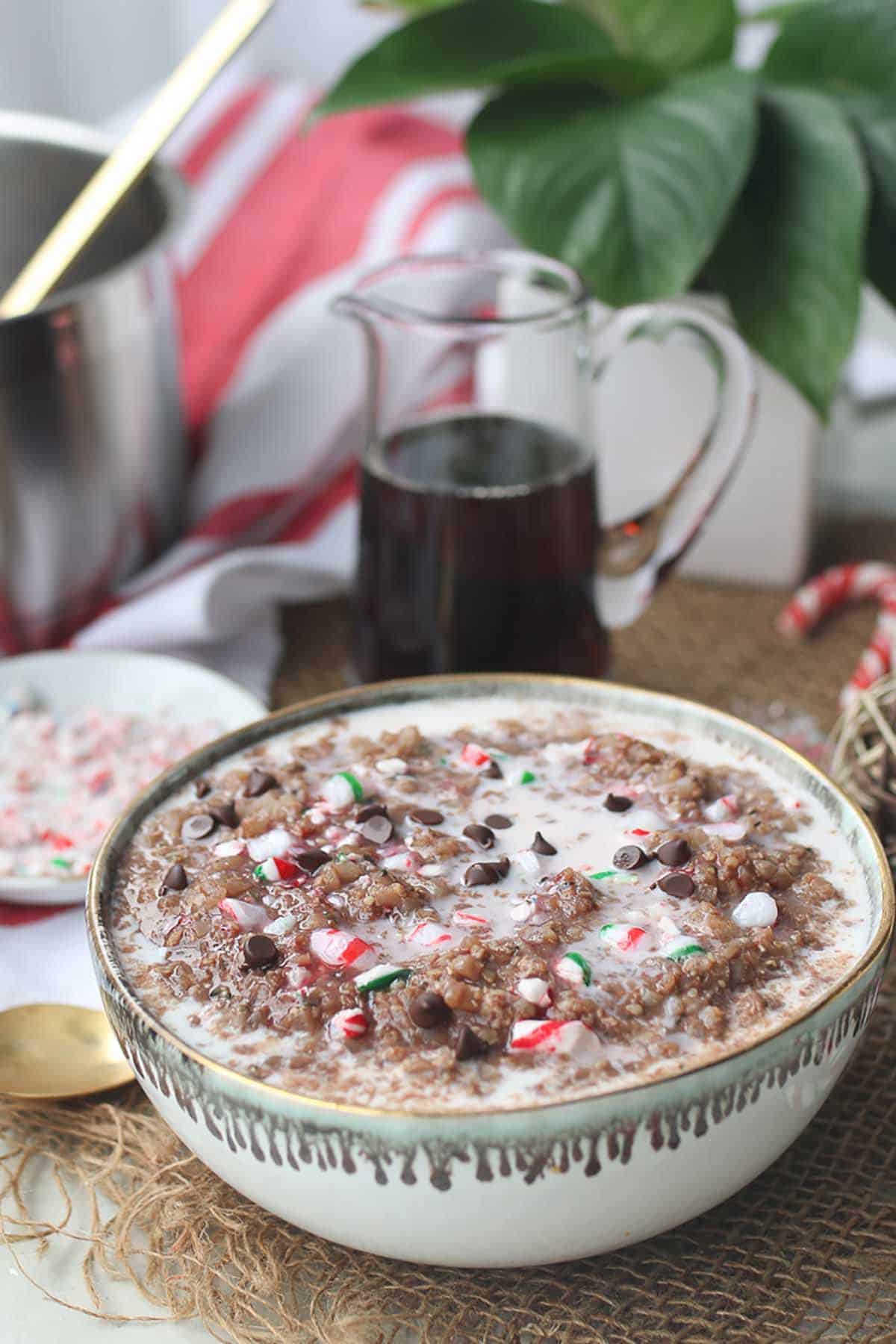 Christmas porridge in a white bowl topped with chocolate chips and candy canes. 