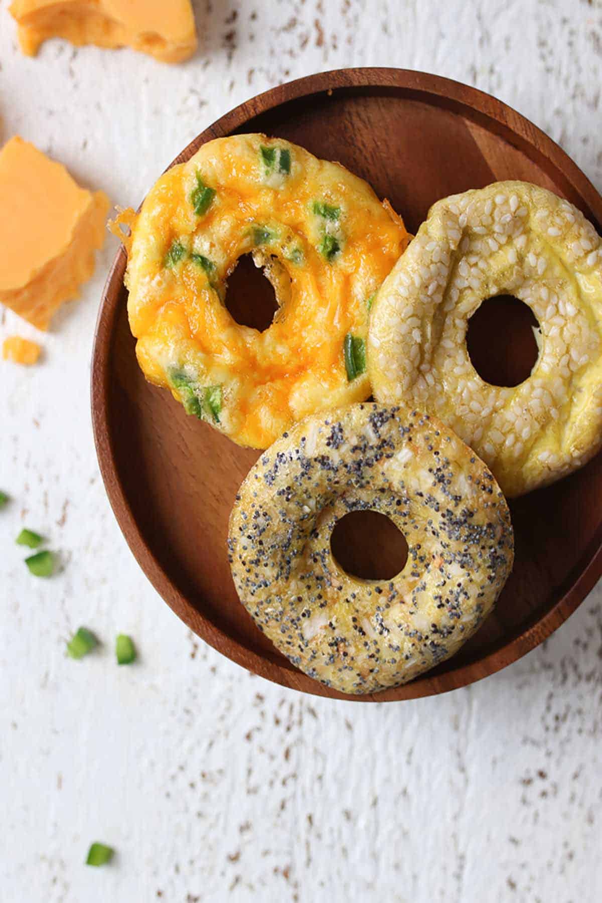 Three egg bagels on a wooden plate. 