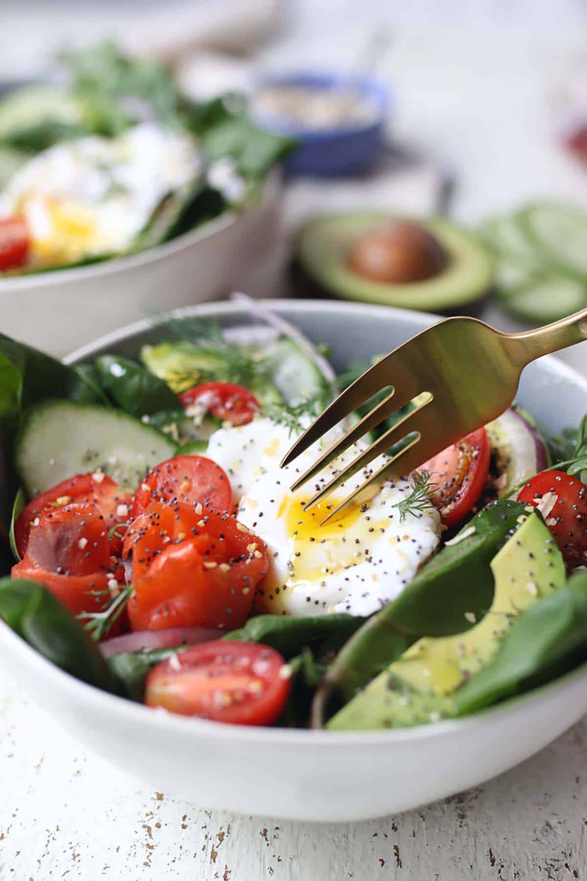 A fork cutting into a poached egg on a salad.